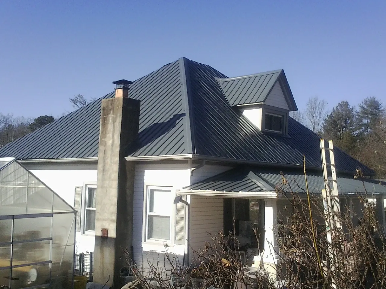 Dark blue standing seam metal roof on a white farmhouse with dormer — Slate & Tile Roof Repair by Roofing Brothers in Mount Carmel